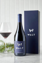 Photo of the WALT 2023 Bob's Ranch Gift set containing a bottle of 2023 WALT Bob's Ranch Pinot Noir and a Blue WALT branded gift box next to a glass of red wine.